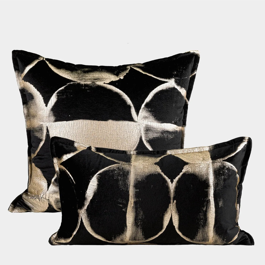 Black and gold abstract patterned flannel sofa cushion with removable cover on a grey sofa.