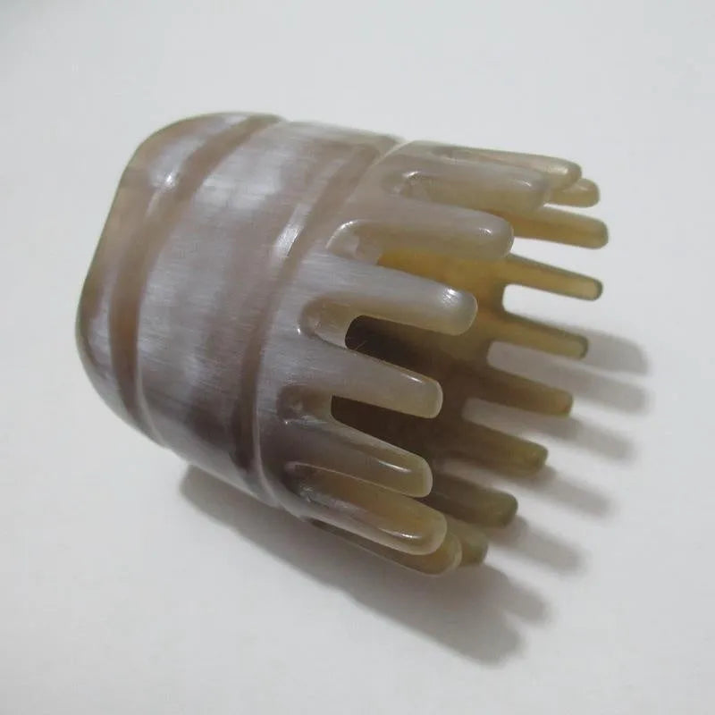 A white buffalo horn comb with wide teeth and a pointed tip for scalp massage.