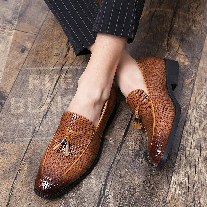 Men's black pointed toe slip on loafers with a tassel detail on the front, shown on a plain background.