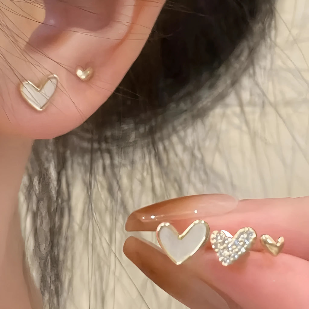 Three pairs of women's heart-shaped alloy earrings in gold, black, black-white, and pink colours