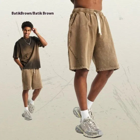Man wearing loose fit batik-dyed cotton terry shorts in a casual street fashion setting.