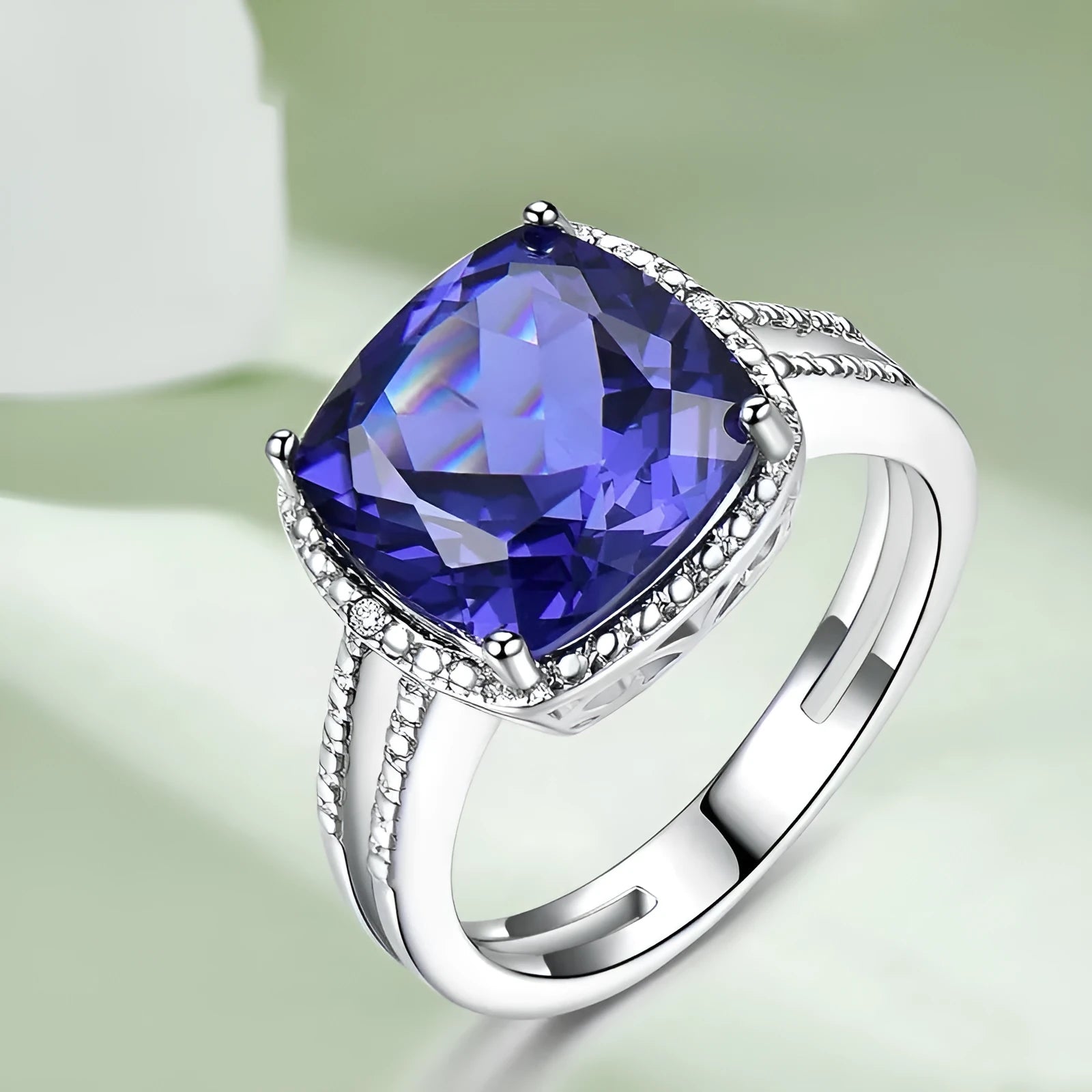 Close-up of a blue tanzanite stone set in a sterling silver women's ring on a grey background.