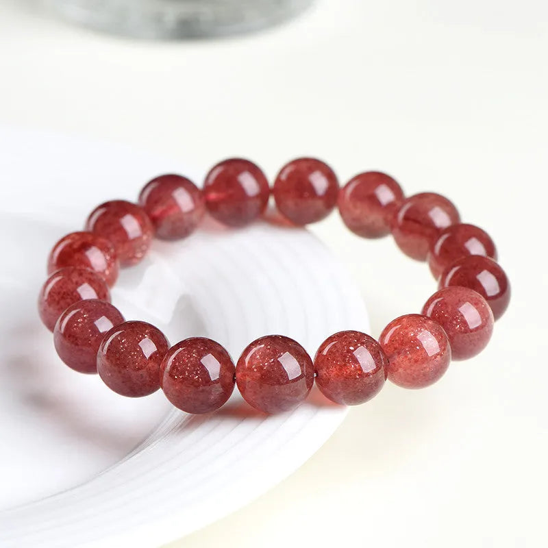 Natural strawberry quartz bracelet with geometry-shaped beads in starlight cherry red colour on a wrist.