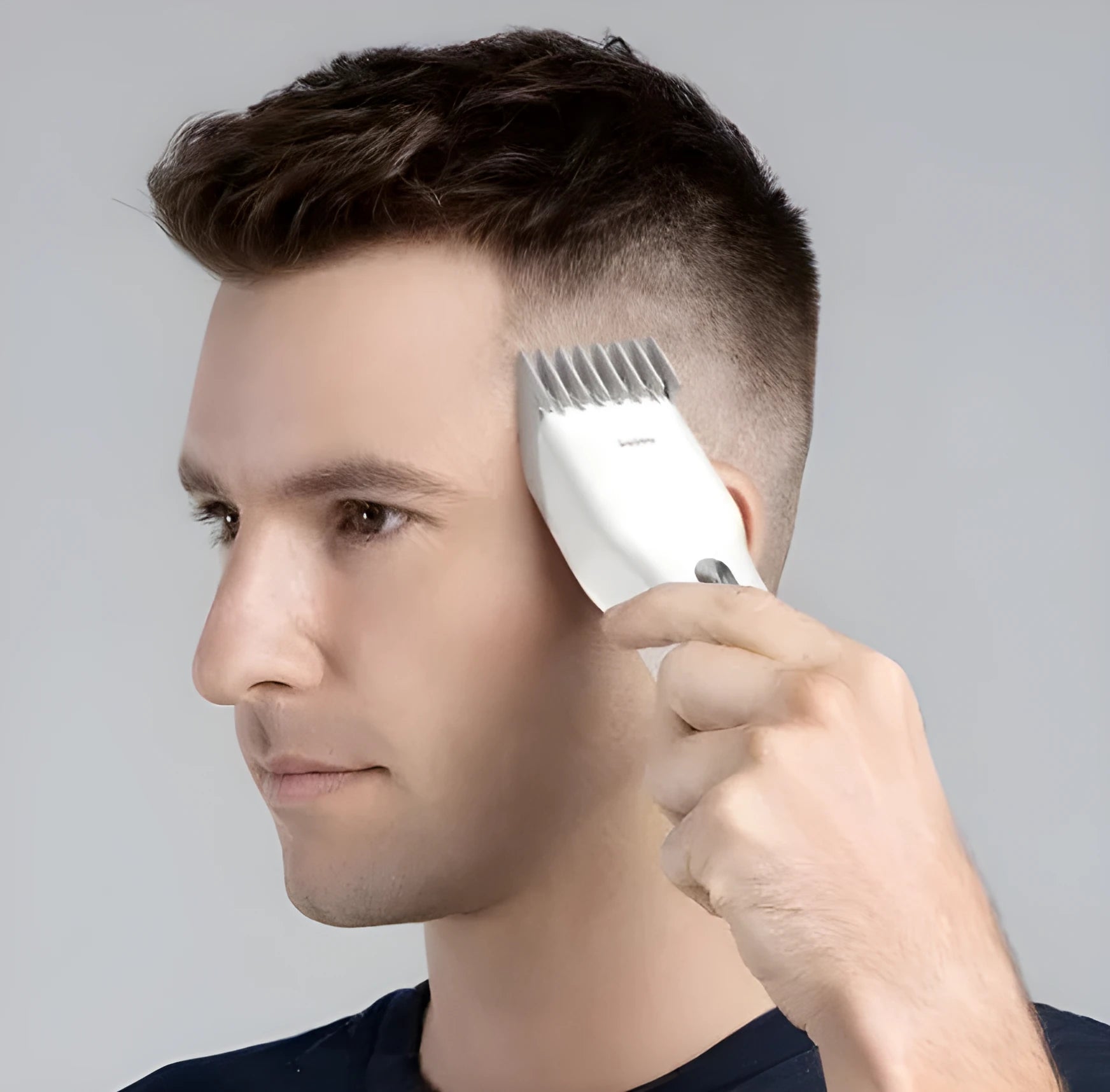 Black and white Boost model cordless hair clipper with adjustable comb on a stand