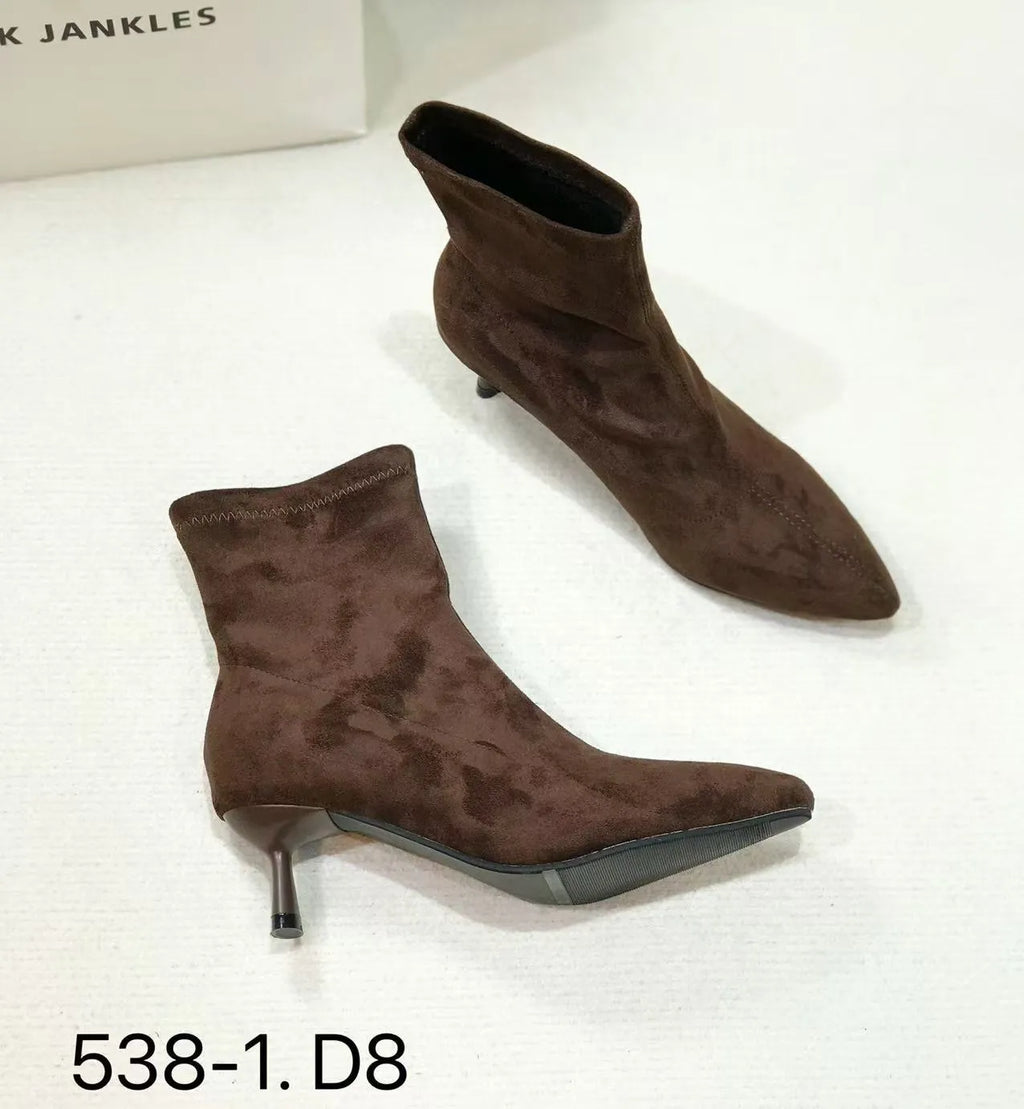 Black pointed toe ankle boots with a high stiletto heel on a woman's foot.