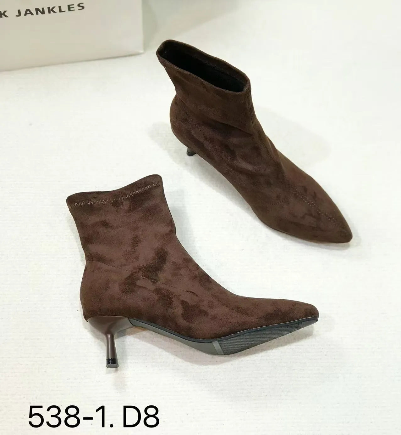 Black pointed toe ankle boots with a high stiletto heel on a woman's foot.