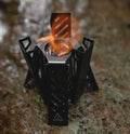 Hexagon-shaped foldable alcohol camping stove in black or silver, measuring 9.5x8.5x15cm
