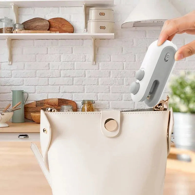 Blue and white handheld USB rechargeable food sealer with magnetic back and cutter blade.