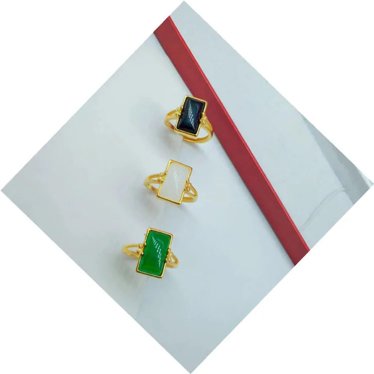 Adjustable brass gold-plated ring with a centre gemstone, shown in black, green, and white colour options.