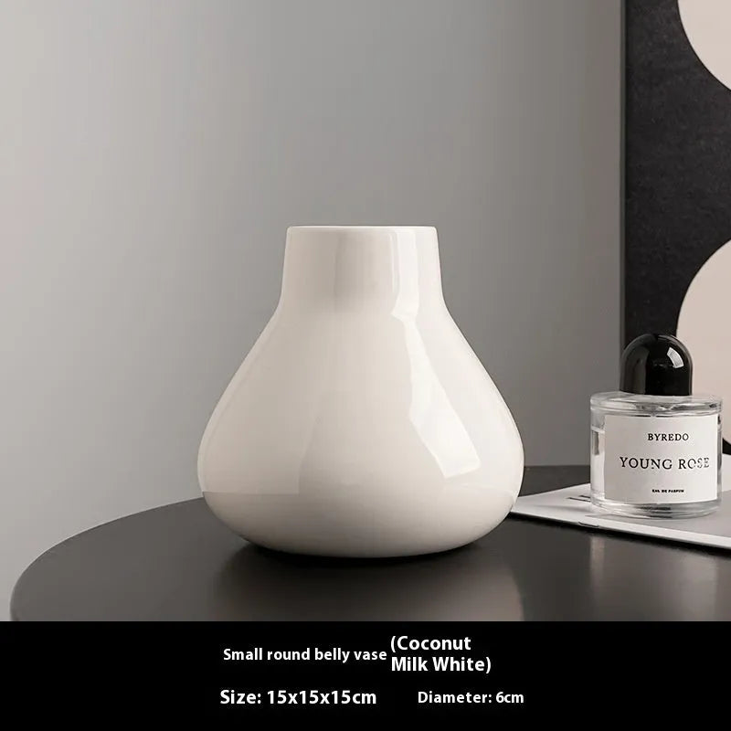 Ceramic round belly vase in black or white with artificial orchid stems on wooden surface