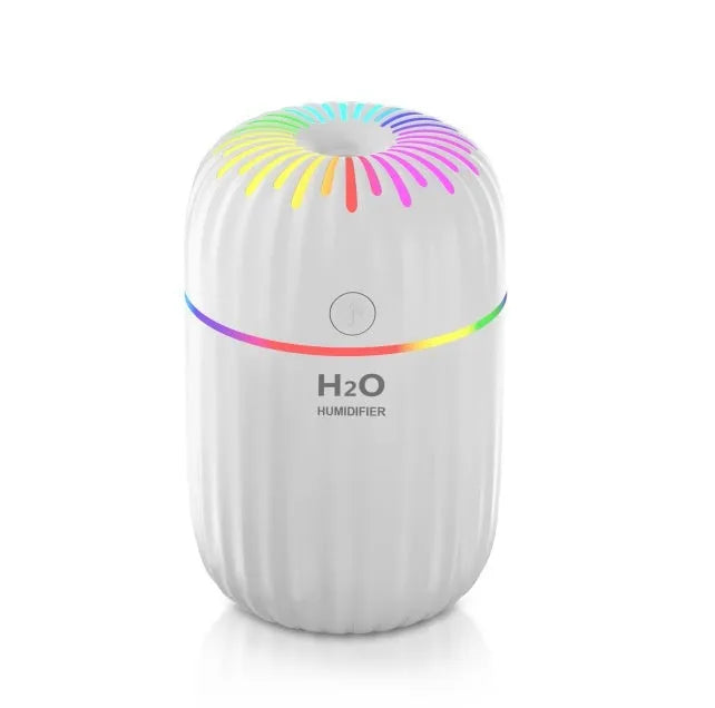 Small white Fireworks USB desktop humidifier with water tank on a wooden desk.