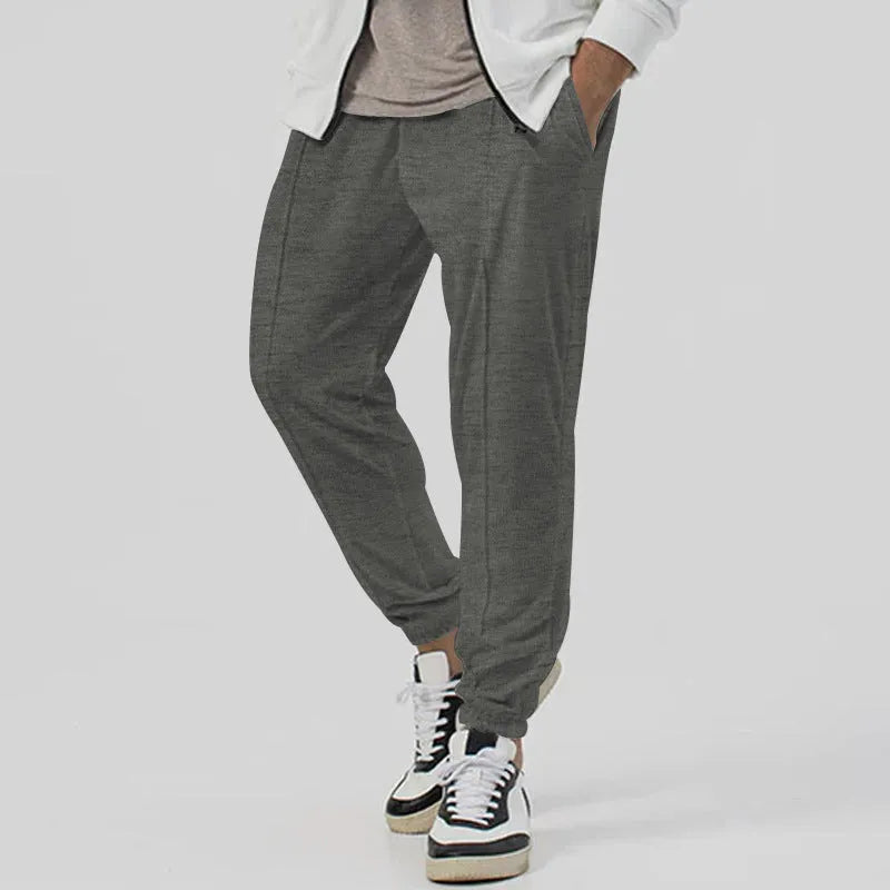 Men's grey casual tapered sweatpants with an elasticated waistband laid flat.