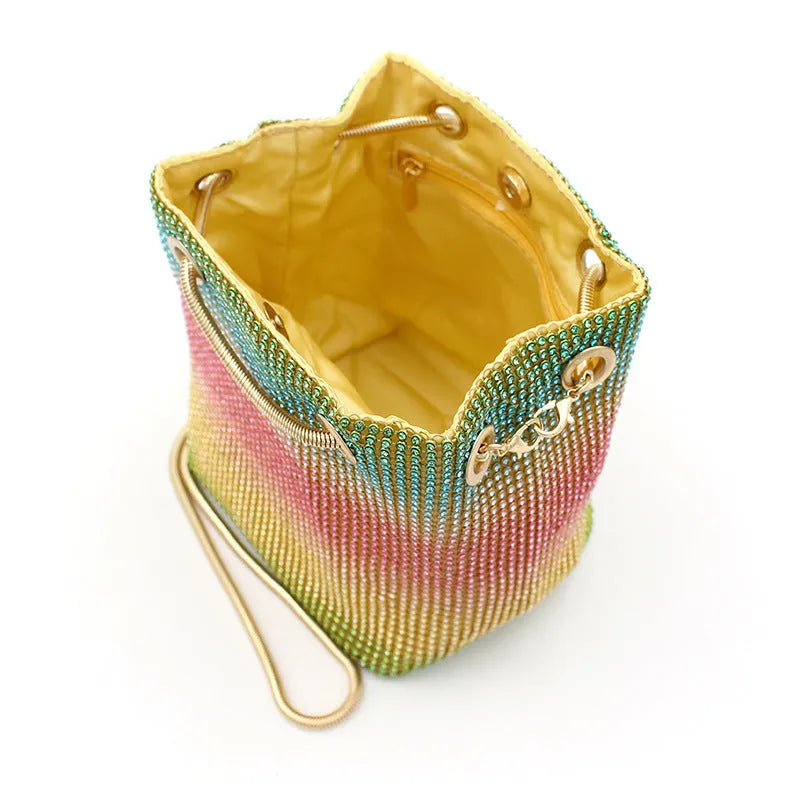 Soft rainbow-coloured rhinestone bucket bag with a silver chain shoulder strap on a white background.