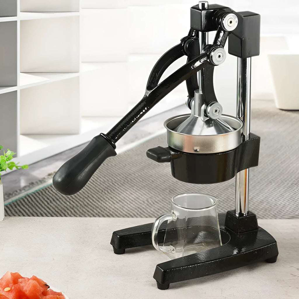 Black or white manual cast iron citrus juicer with stainless steel funnel on a kitchen counter.