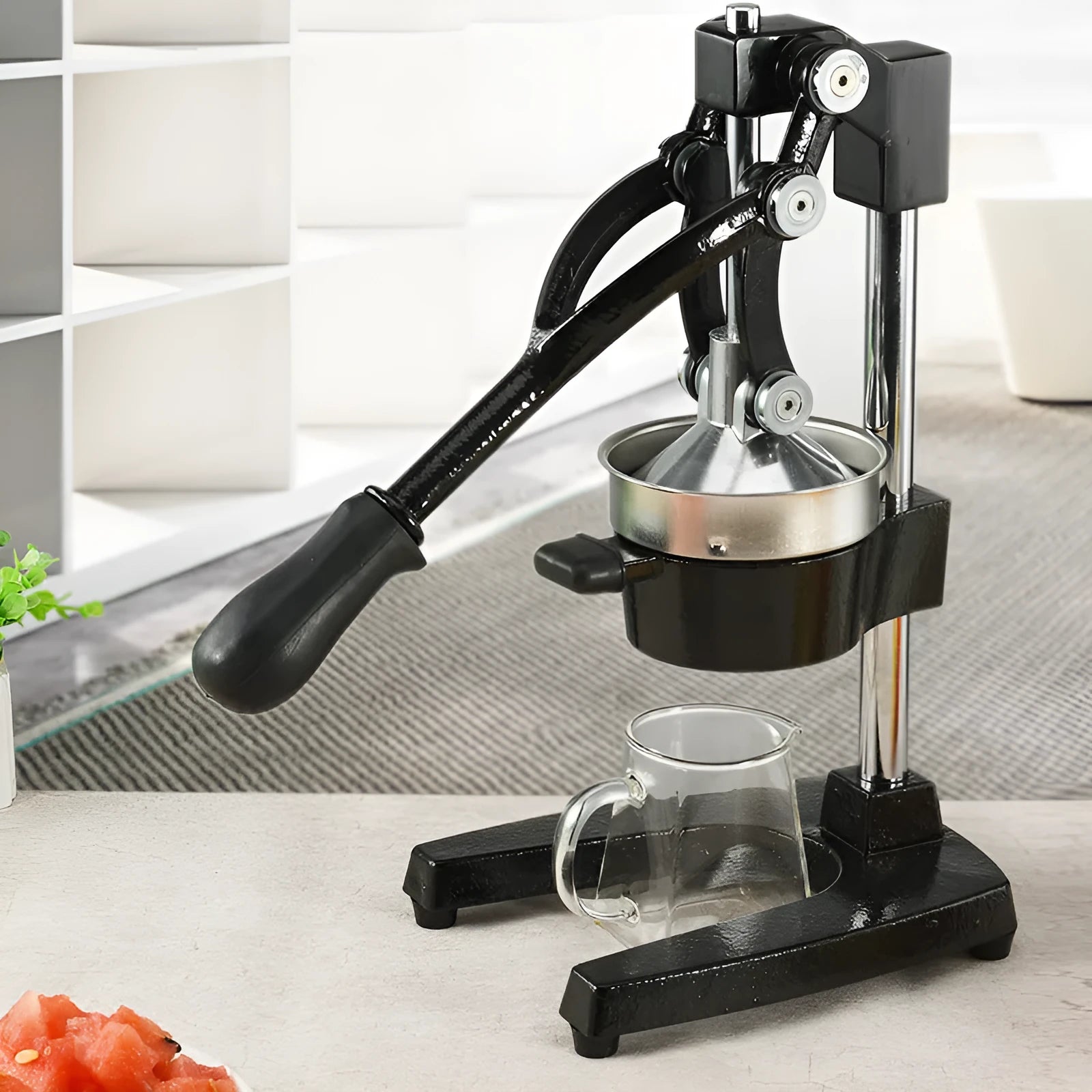 Black or white manual cast iron citrus juicer with stainless steel funnel on a kitchen counter.