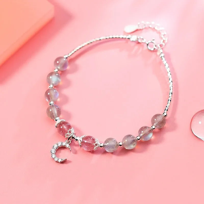 Handmade adjustable moonstone bracelet with crescent moon charm and crystal bead on wrist.