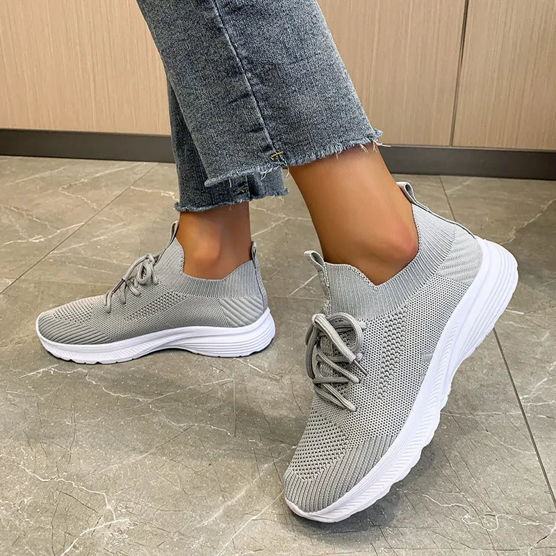 Women's mesh running shoes in creamy white with Flyknit upper and flat rubber sole