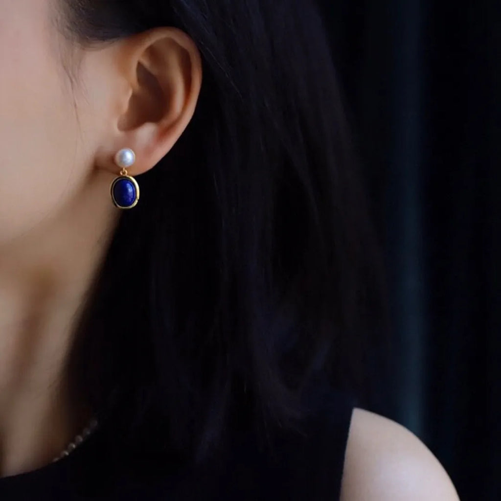 A pair of simple stud earrings with a blue lapis lazuli pearl set in sterling silver.