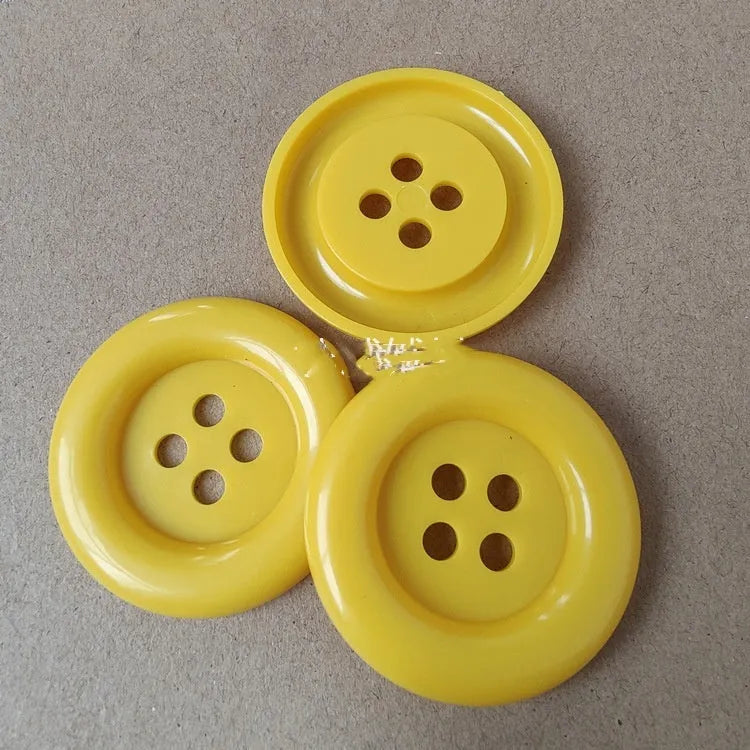 Oversized round plastic button with four holes in various colours and sizes from 38mm to 70mm.