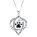 Close-up of a copper necklace pendant showing detailed dog and cat paw prints on a cross chain.