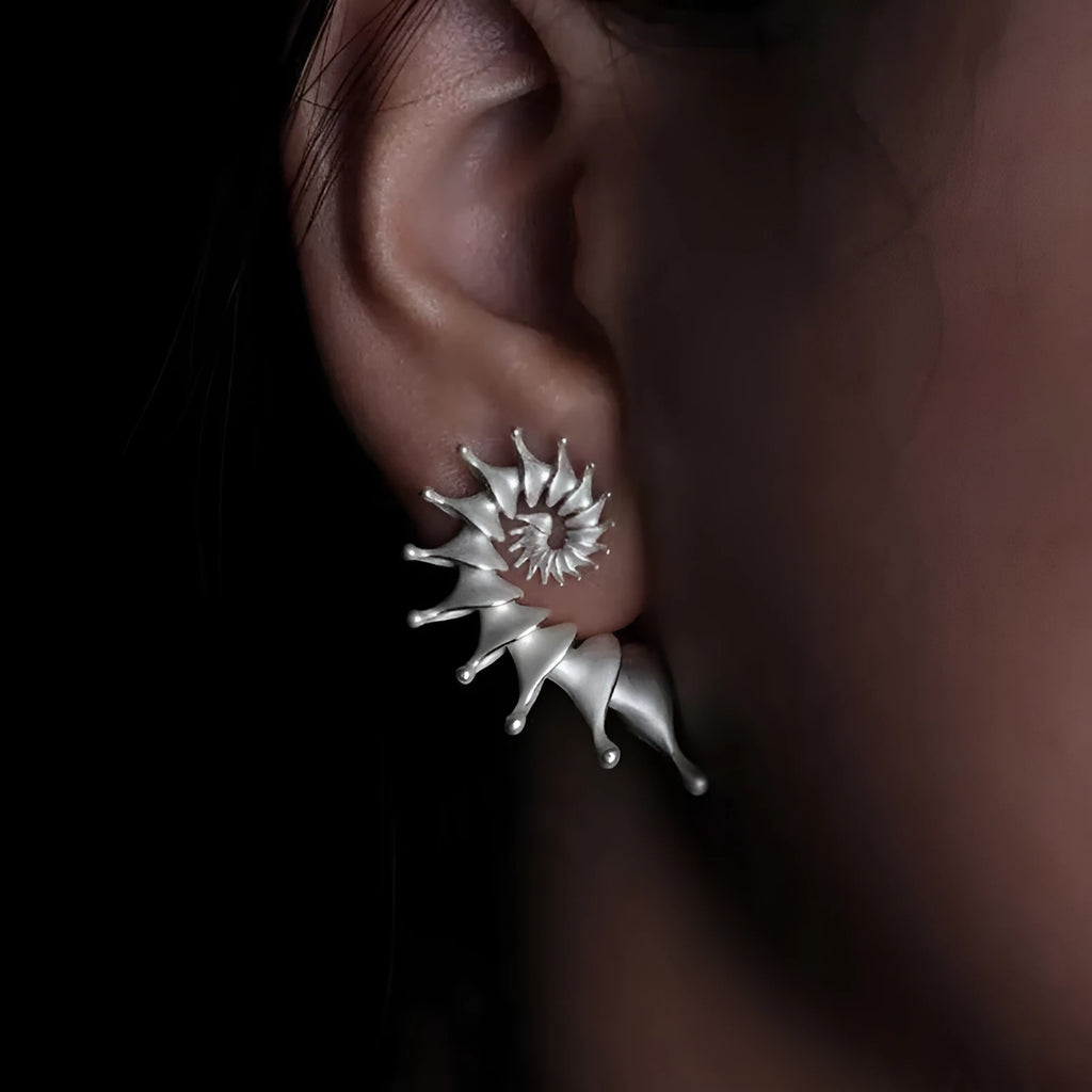 A pair of matte conch-coloured alloy stud earrings with an exaggerated three-dimensional shape.
