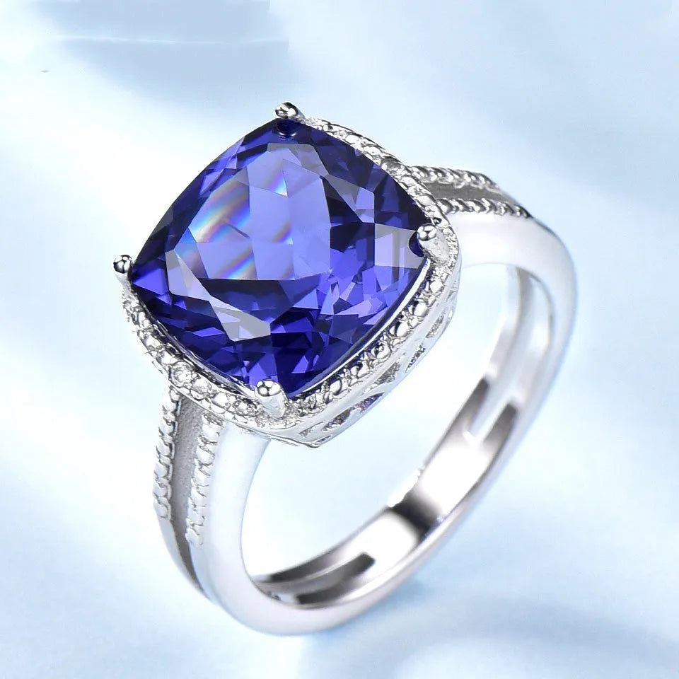 Close-up of a blue tanzanite stone set in a sterling silver women's ring on a grey background.
