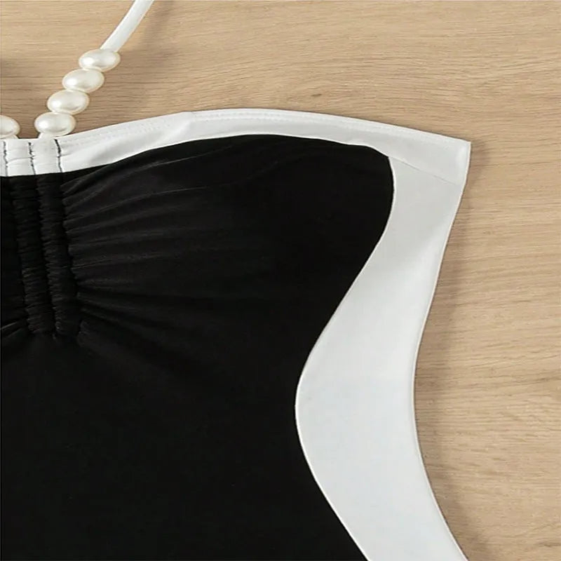 Black and white women's one-piece swimsuit with slim fit and pearl spaghetti straps on a mannequin.