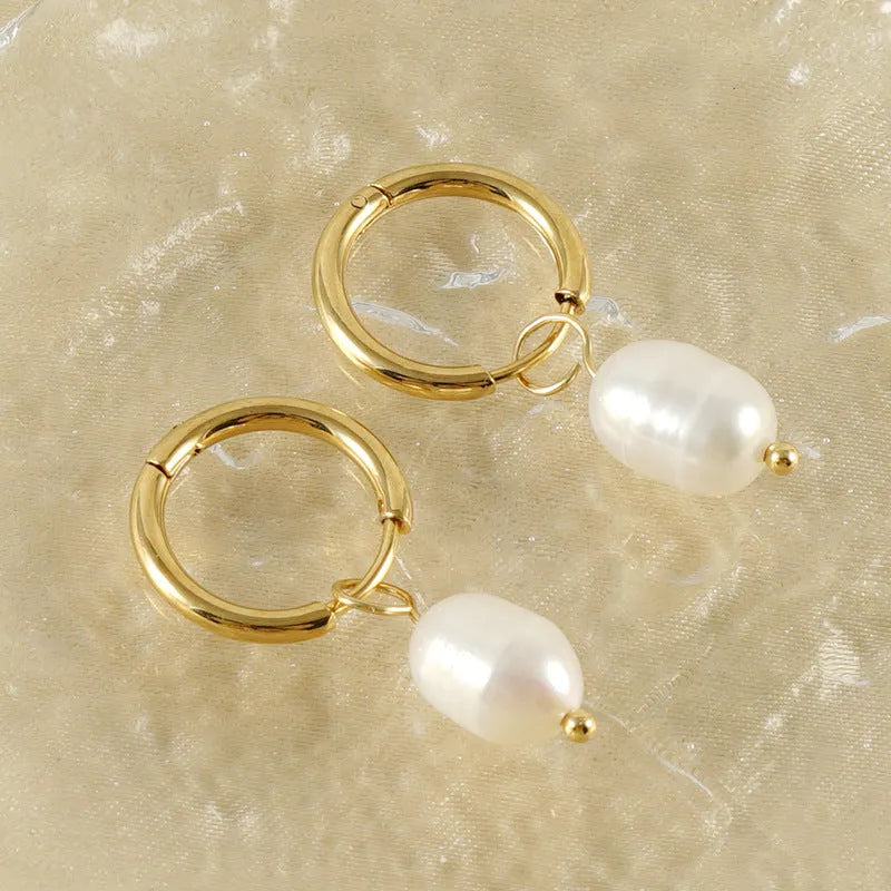 Geometric gold-coloured earrings with cultured pearl details on a white background.
