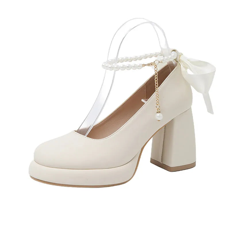 Women's beige Mary Jane shoes with chunky heel, round toe, and ankle strap with pearl buckle.