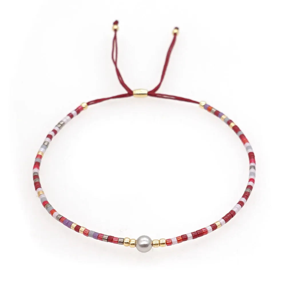 Women's handmade bohemian bracelet with colourful geometric glass and glaze beads on a wrist.