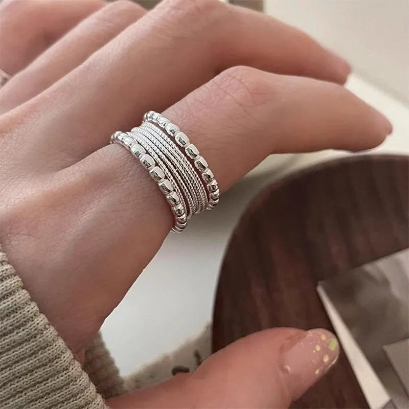 Adjustable geometric copper alloy ring with woven twisted multilayer design on a woman's hand.