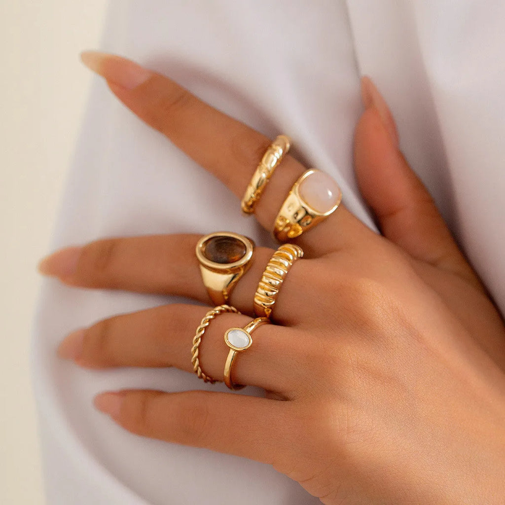 Six geometric alloy rings with light gold electroplated finish arranged irregularly