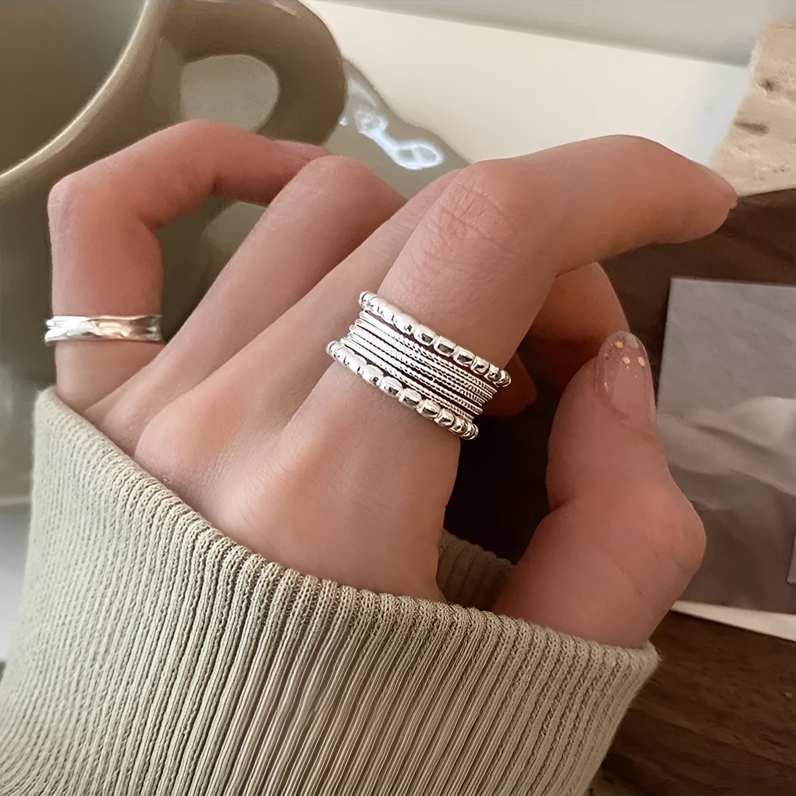 Adjustable geometric copper alloy ring with woven twisted multilayer design on a woman's hand.