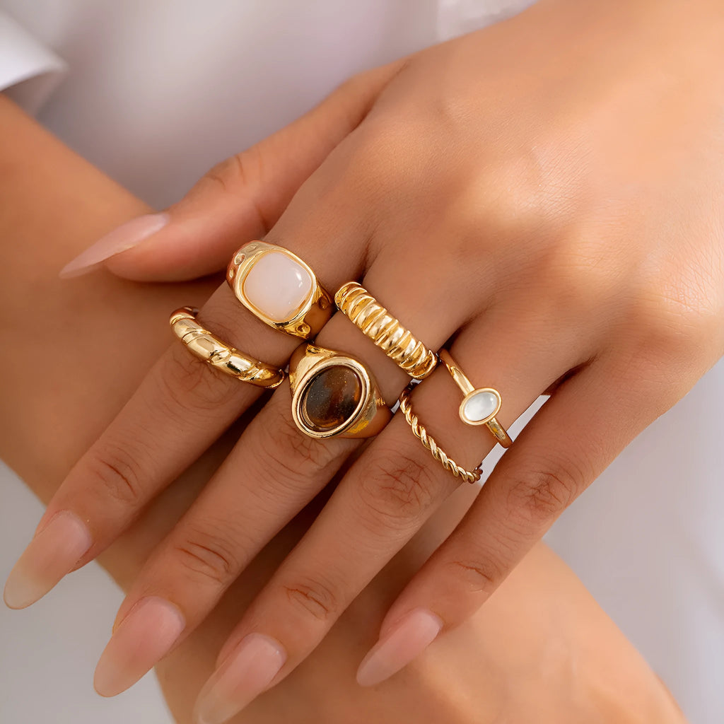 Six geometric alloy rings with light gold electroplated finish arranged irregularly