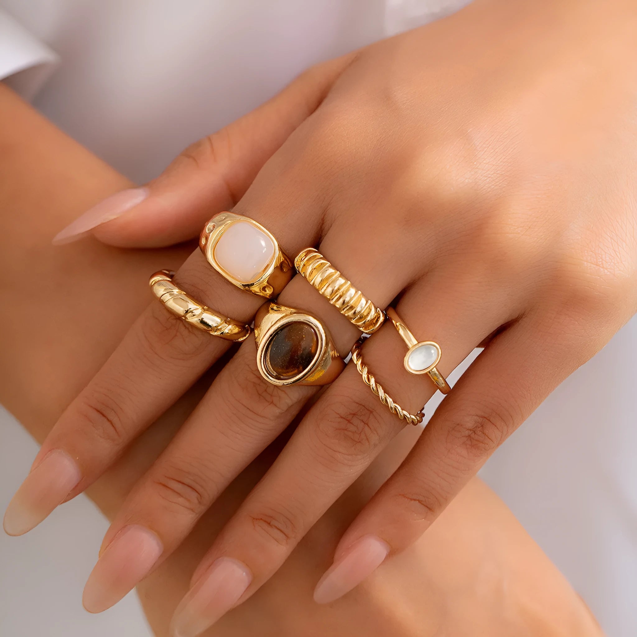 Six geometric alloy rings with light gold electroplated finish arranged irregularly