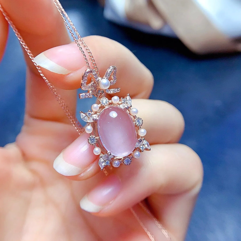 Close-up of a geometric silver pendant with a pink rose quartz stone and rose gold plating on a chain.