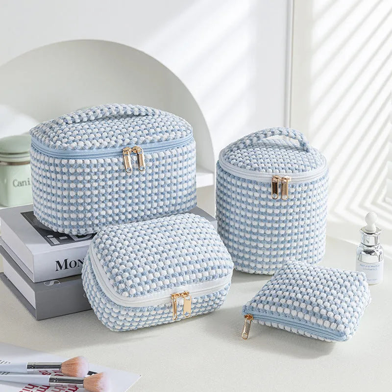 Four cube-shaped polyester makeup bags in coordinated set for cosmetics organisation