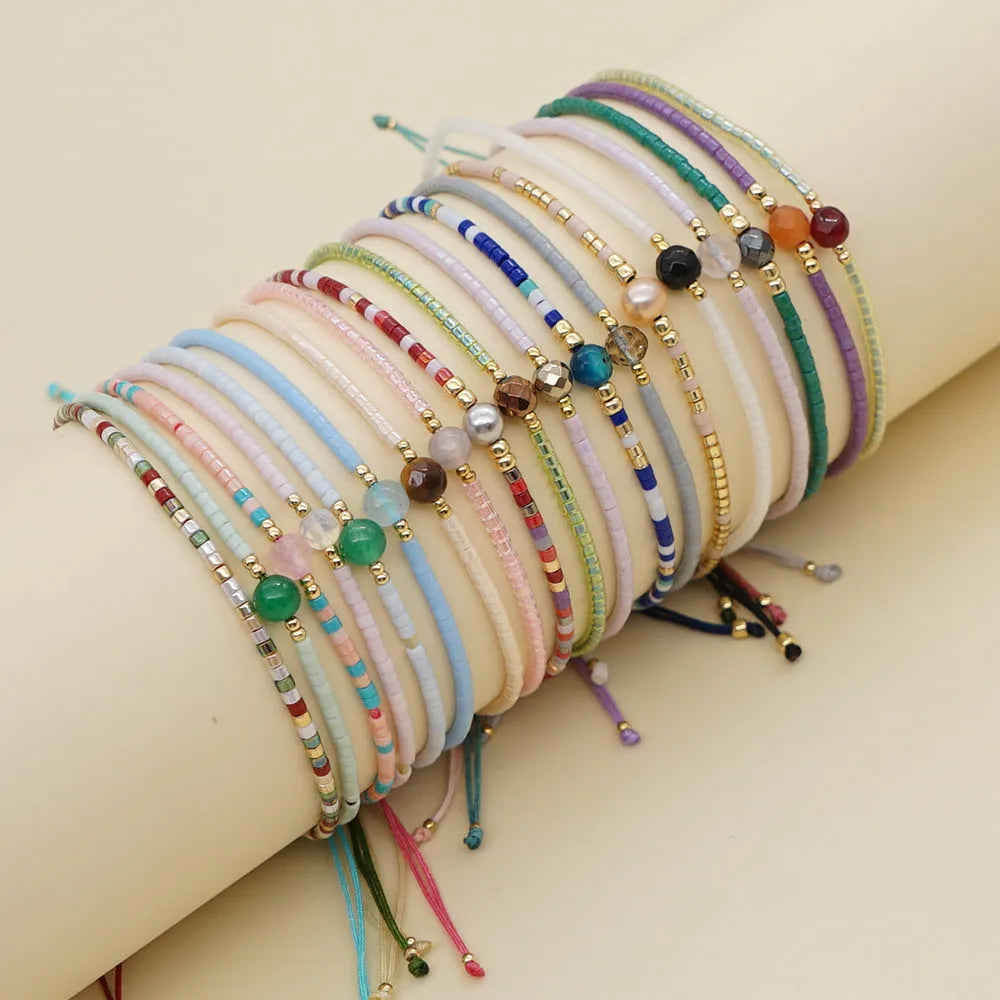 Women's handmade bohemian bracelet with colourful geometric glass and glaze beads on a wrist.