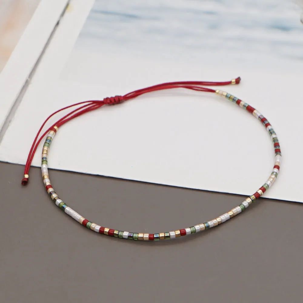 Women's handmade bohemian bracelet with colourful geometric glass and glaze beads on a wrist.