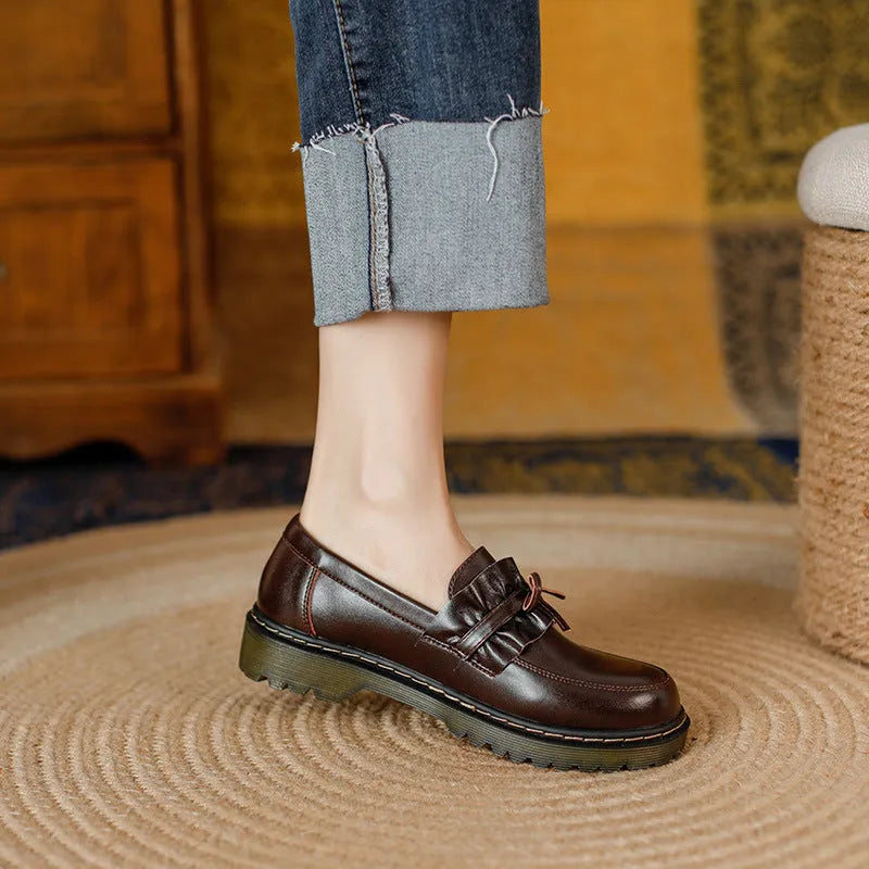 Black and brown women's round toe leather shoes with a chunky flat heel and low upper.
