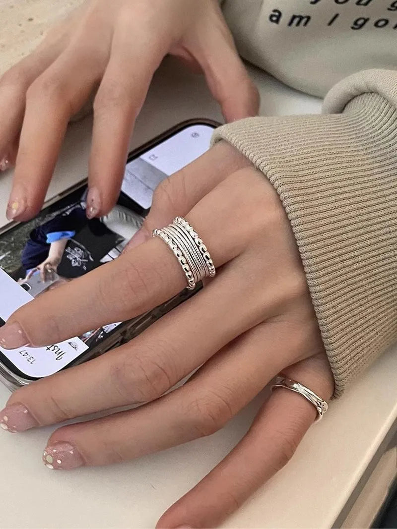 Adjustable geometric copper alloy ring with woven twisted multilayer design on a woman's hand.