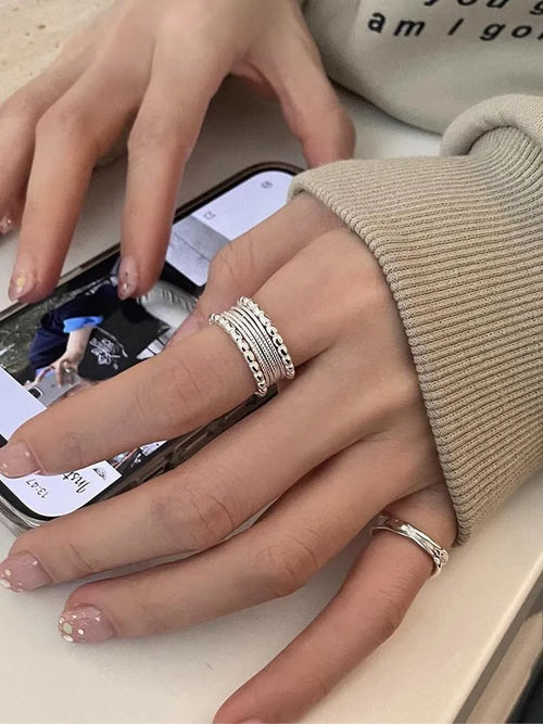 Adjustable geometric copper alloy ring with woven twisted multilayer design on a woman's hand.