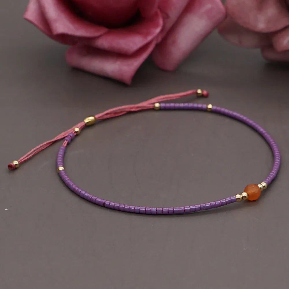 Women's handmade bohemian bracelet with colourful geometric glass and glaze beads on a wrist.