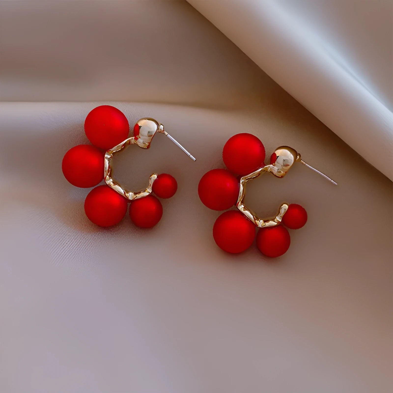 A pair of red alloy drop earrings featuring a small bell charm on a stud fitting.