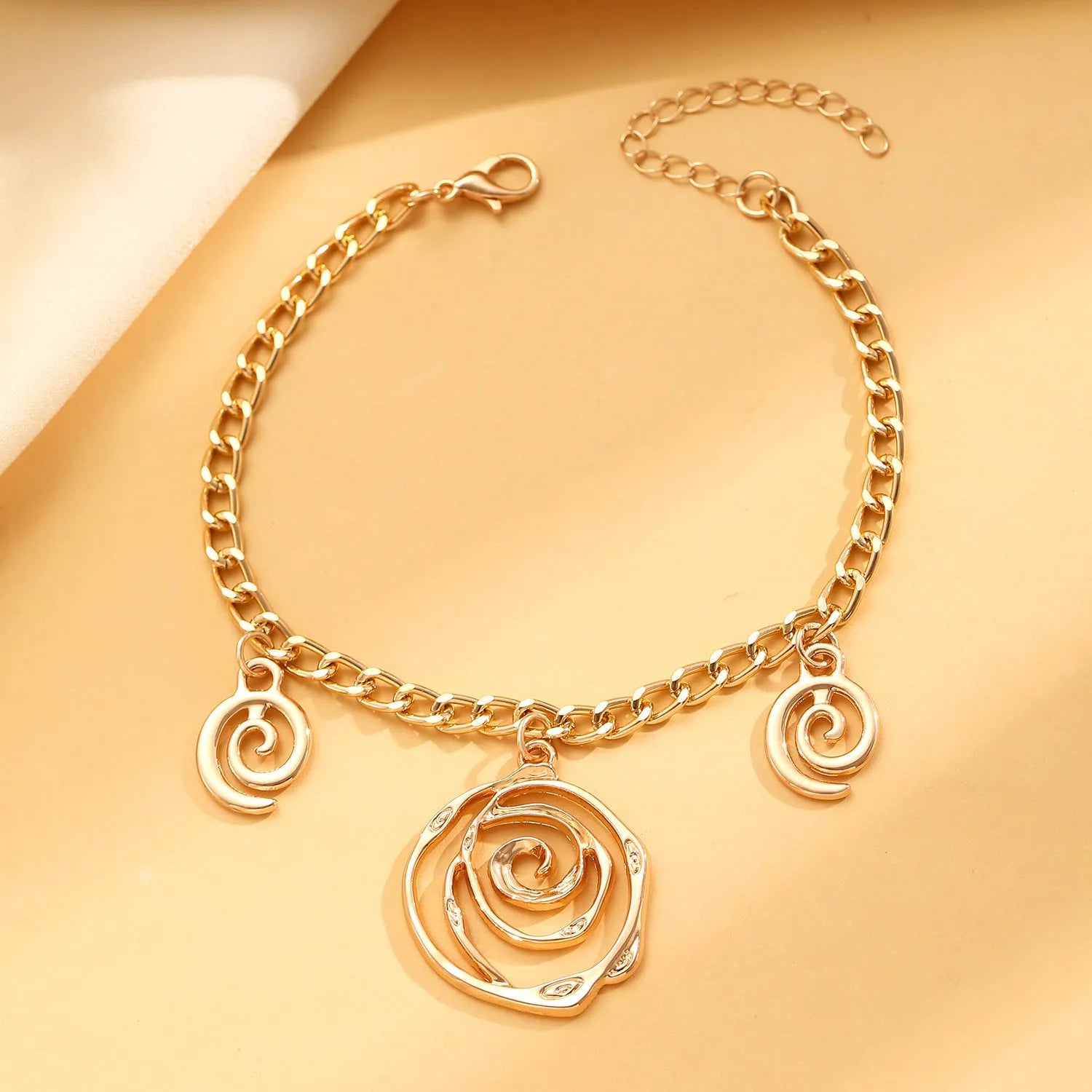 Women's spiral donut jewellery set showing bracelet, earrings, and adjustable necklace in gold tone