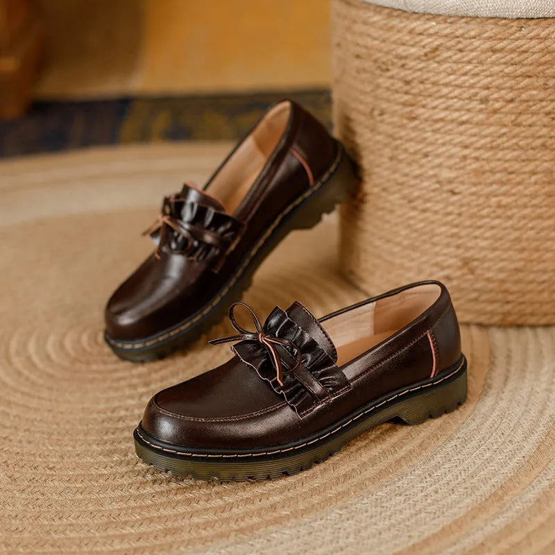 Black and brown women's round toe leather shoes with a chunky flat heel and low upper.