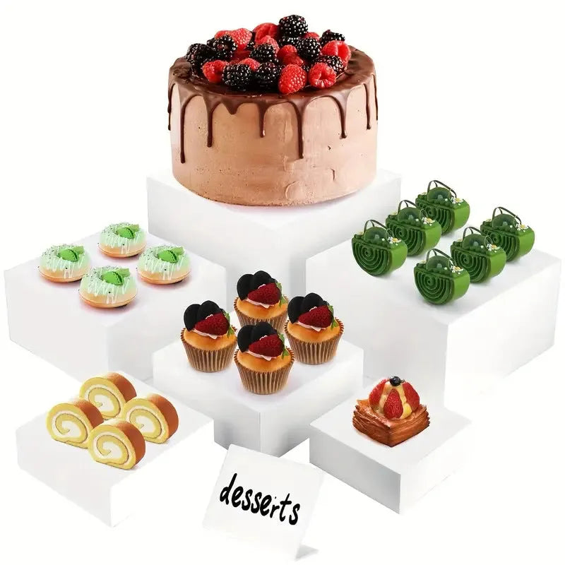 Six white plastic cube dessert display stands in graduated sizes from 3 to 8 centimetres.