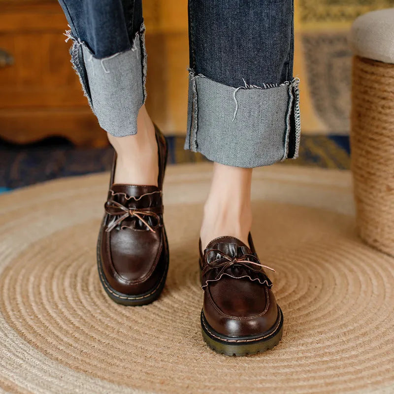Black and brown women's round toe leather shoes with a chunky flat heel and low upper.