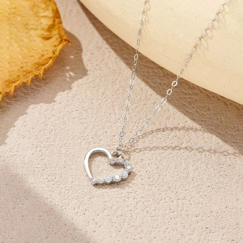 Close-up of a women's sterling silver hollow heart necklace with a circle detail, showing the white gold finish option.