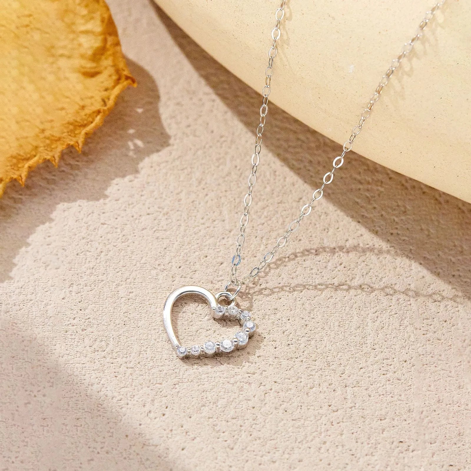 Close-up of a women's sterling silver hollow heart necklace with a circle detail, showing the white gold finish option.